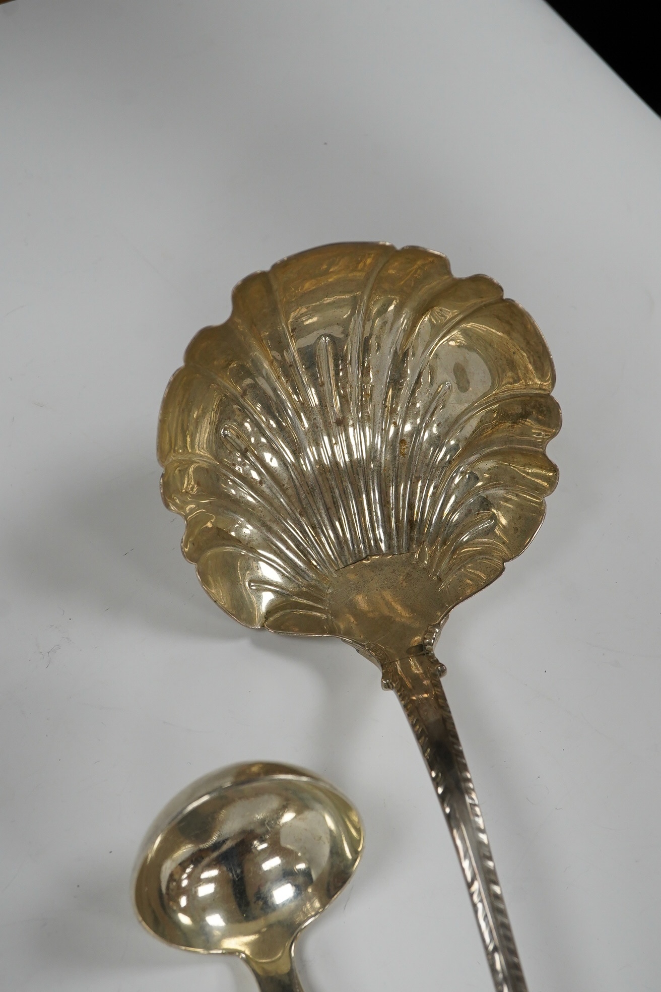 An early George III silver Old English feather edge pattern soup ladle, George Baskerville, London, 1766, together with a Victorian Scottish silver sauce ladle, 6.1 oz. Condition - poor to fair